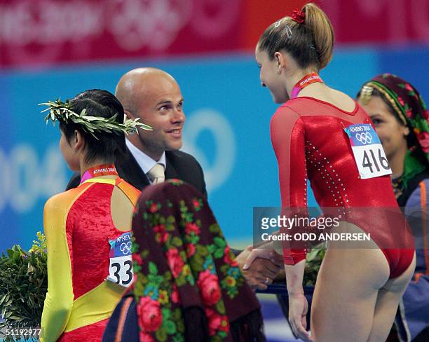 Former Norwegian Olympic speedskater Aadne Soendraal shakes hands with gold medallist Carly Patterson of the US as bronze medallist Zhang Nan looks...