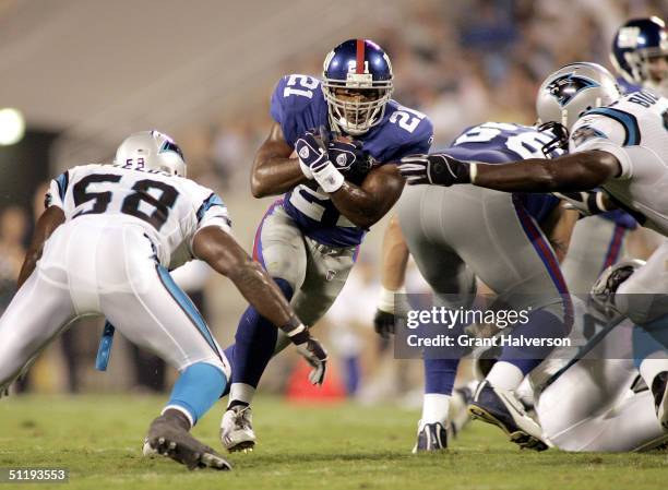 Tiki Barber of the New York Giants runs between Mark Fields and Brentson Buckner of the Carolina Panthers during a NFL game on August 19, 2004 at...