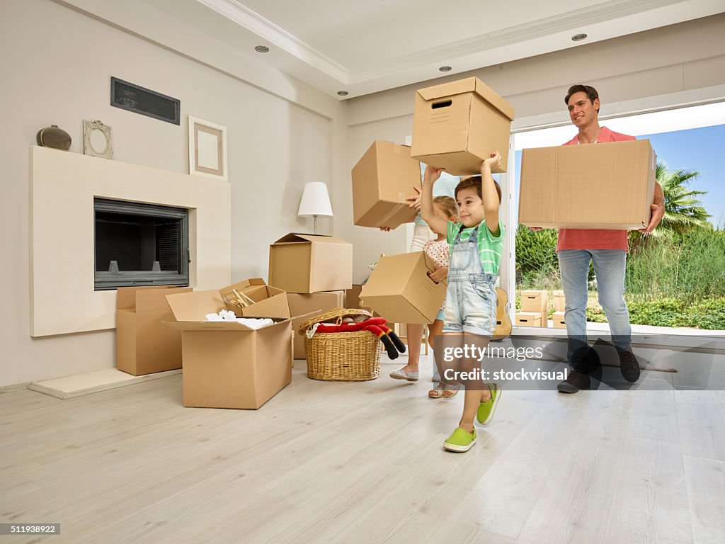 Family carrying large cardboard boxes into new home, portrait