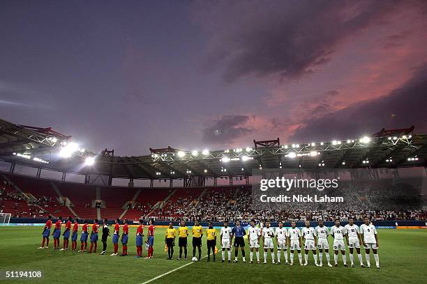 Members of the Costa Rican and Iraqi teams stand with the officials as each team's National Anthem is played before the men's football preliminary...