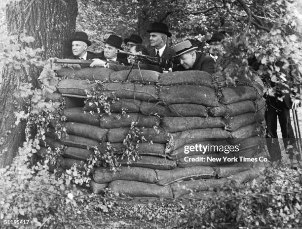 MPs practice 'spotting' from behind a wall of sandbags whilst visiting a Home Guard instruction centre, 21st August 1940. Pictured are Mr 'Charlie...