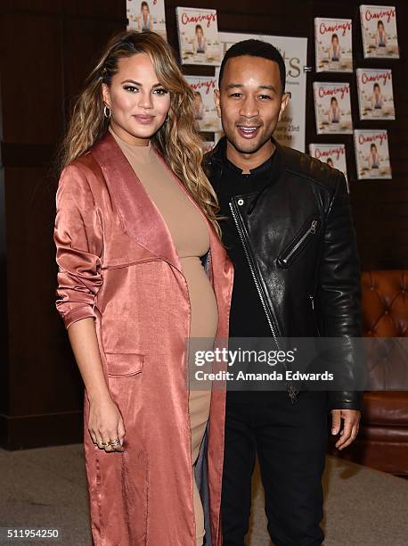 Model Chrissy Teigen and musician John Legend pose together before Teigen signs copies of her book "Cravings: Recipes For All The Food You Want To...