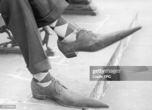 Pair of feet clad in lace-up shoes with long pointy toes, 1960.