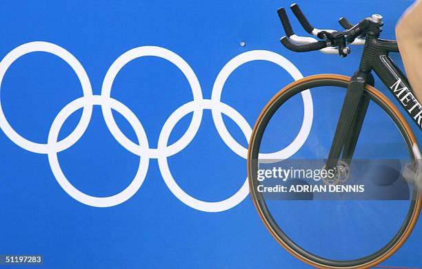 Cyclist warms up beside the Olympic rings before the men's individual pursuit qualifying against Australian Bradley McGee at the Athens velodrome...