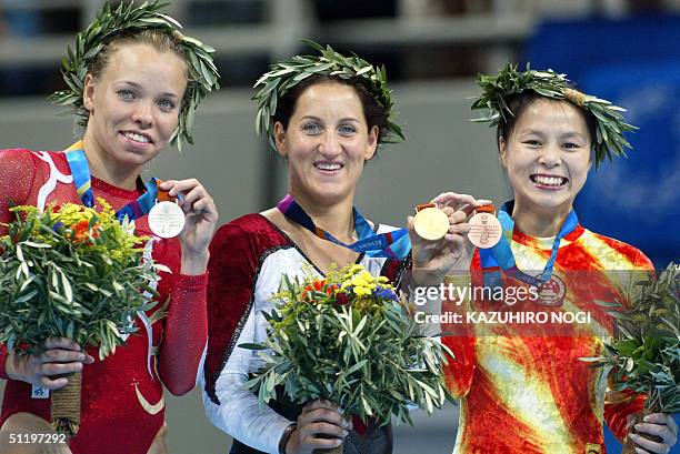 Anna Dogonadze of Germany, winner of the women's trampoline final, shows her gold medal with silver medallist Karen Cockburn of Canada and bronze...