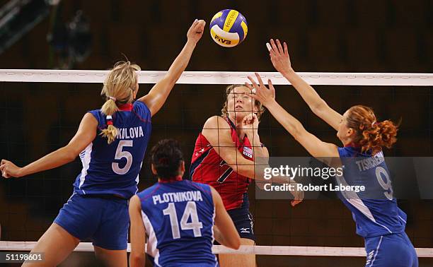 Heather Bown of the USA spikes the ball as Lioubov Shashkova and Elizaveta Tishchenko of Russia try to block it as Elena Plotnikova looks on during...