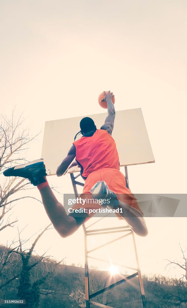 Young man jumping to score hoop in basketball