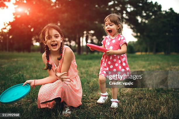 dos hermanas jugando disco volador a disfrutar de un día de campo - frisbee fotografías e imágenes de stock