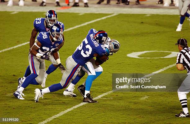 Wesly Mallard of the New York Giants tackles Muhsin Muhammad of the Carolina Panthers in a game on August 19, 2004 at Bank Of America Stadium in...