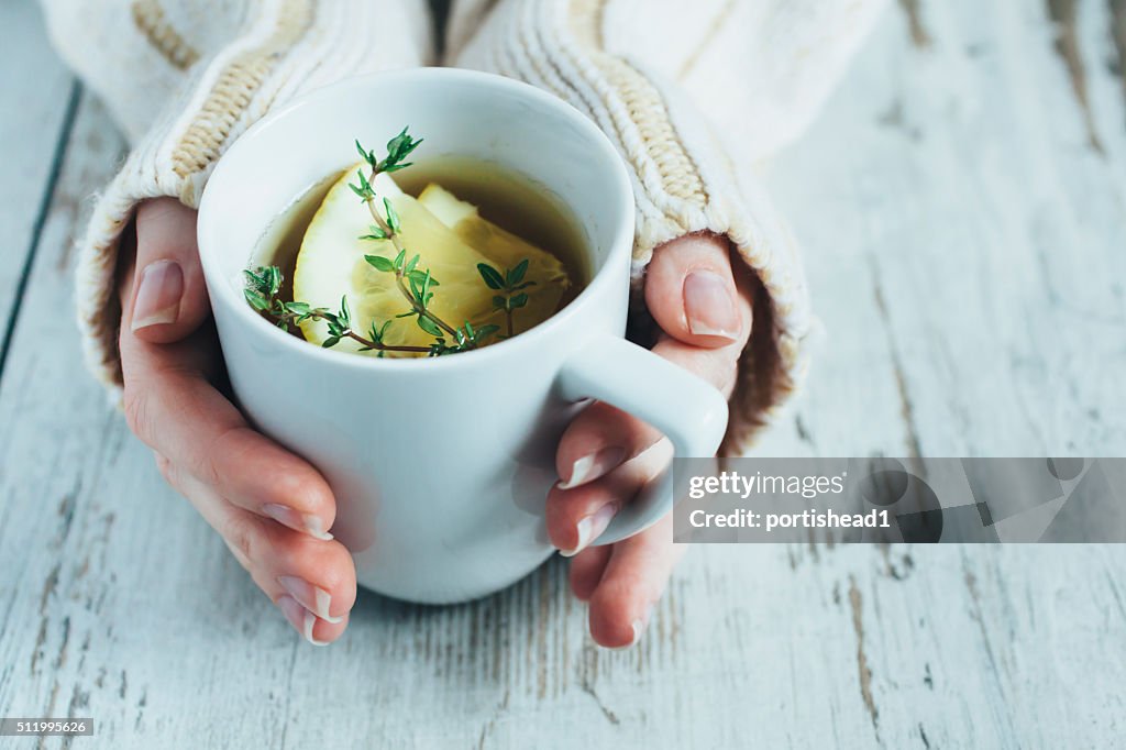Cup of tea with thyme herb and lemon slices