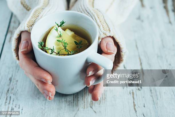 cup of tea with thyme herb and lemon slices - woman drinking tea stockfoto's en -beelden