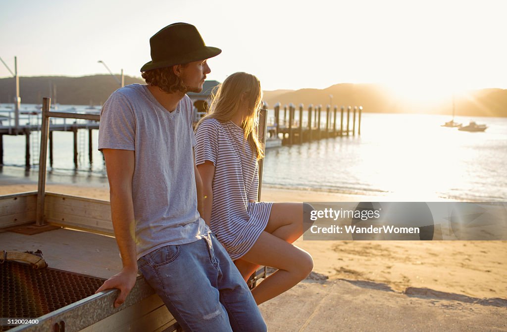 Young couple sitting on tray back of ute at sunset
