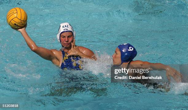 Marina Gritsenko of Kazakhstan is challenged by Ann Dow of Canada for the ball in the women's Water Polo 7th and 8th place classification game on...