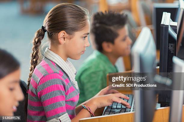 diverse elementary students using computers in school library - digital-library-children stock pictures, royalty-free photos & images