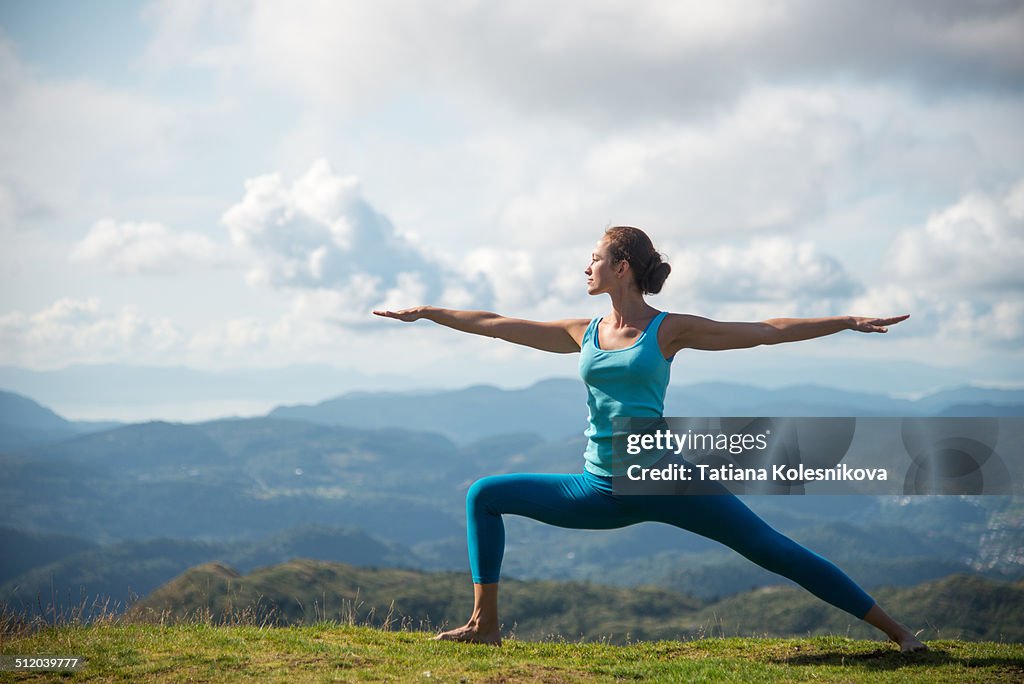 Woman practicing yoga on top of a mountain