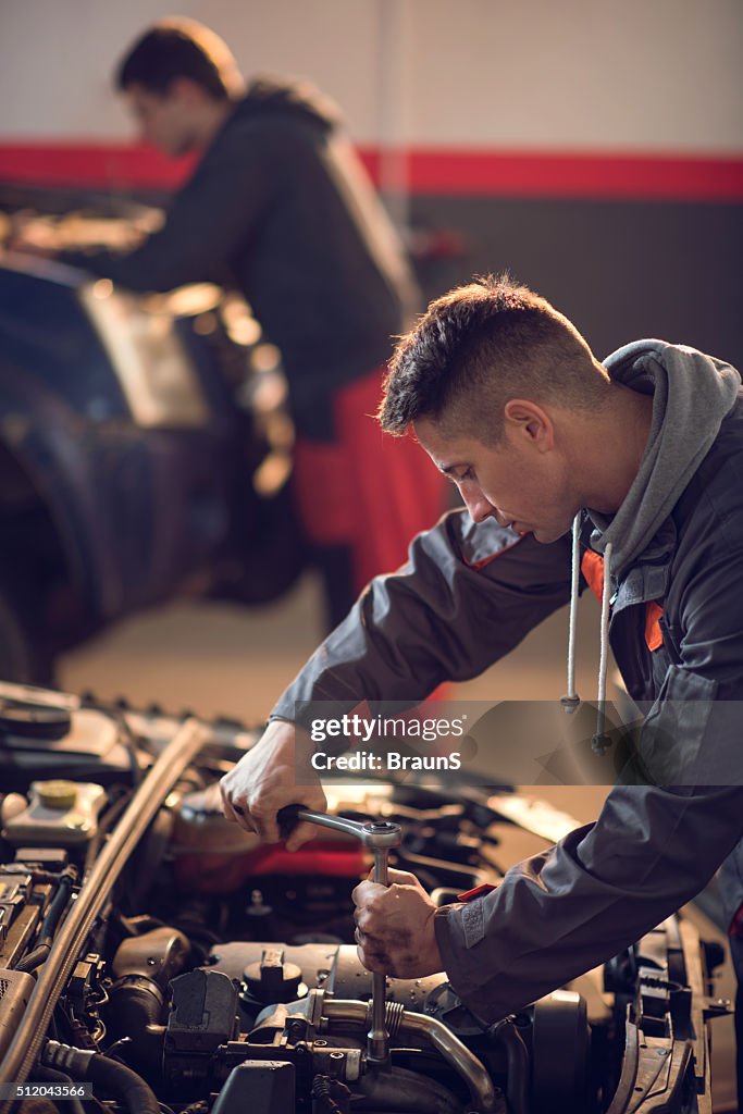 Adulto de idade mediana mecânico reparar um automóvel em oficina de automóvel.