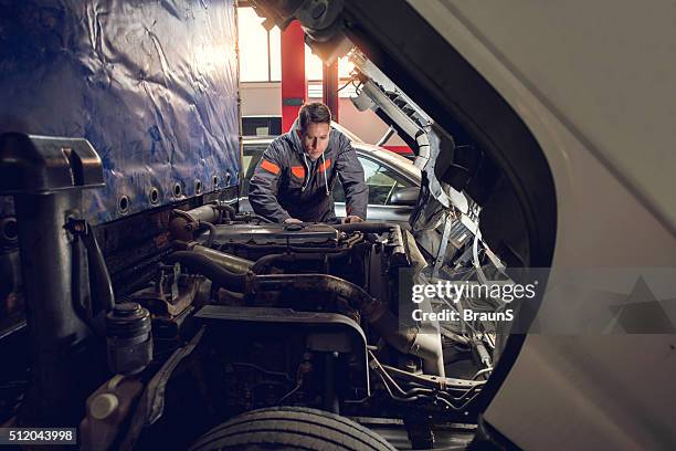 mitte erwachsenen mechaniker reparieren ein lkw in autowerkstatt. - nutzfahrzeug stock-fotos und bilder