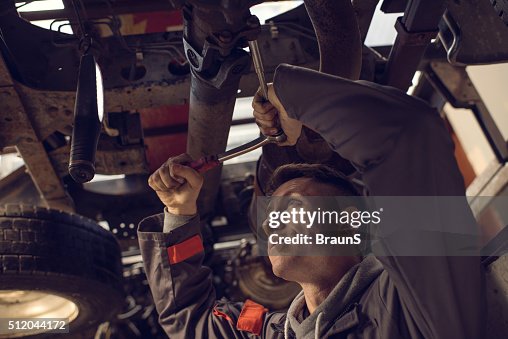 Mechanic using socket wrench while working on a chassis. Mechanic using socket wrench while working on a chassis.