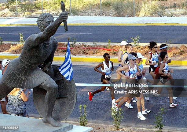 Japan's Mizuki Noguchi leads the pack along with Britain's Paula Radcliffe as they run past a statue depicting a ancient Greek runner during the...