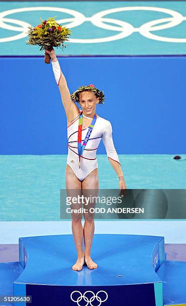 French Emilie Lepennec celebrates on the podium after winning the gold medal in the women's uneven bars final 22 August 2004 at the Olympic Indoor...