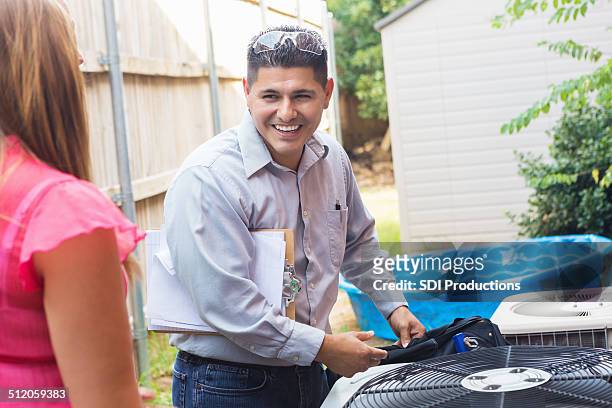 air conditioner repairman talking to homeowner while inspecting unit - air conditioner family stock pictures, royalty-free photos & images