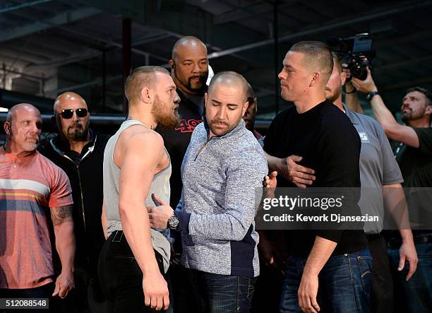 Featherweight champion Conor McGregor and lightweight contender Nate Diaz are held apart by Dave Sholler , UFC vice president of public relations,...