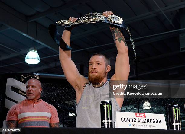 Featherweight champion Conor McGregor holds up the championship belt during a news conference with lightweight contender Nate Diaz at UFC Gym...