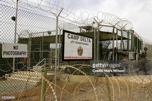 Soldier walks through a gate at Camp Delta at Guantanamo Naval Base August 23, 2004 in Guantanamo, Cuba. On August 24, preliminary hearings will...