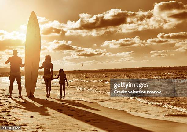 family with surfboard on the beach - destin stock pictures, royalty-free photos & images