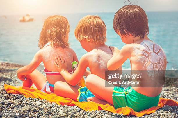 sun protection on the beach - lichaamsverzorging en schoonheid stockfoto's en -beelden