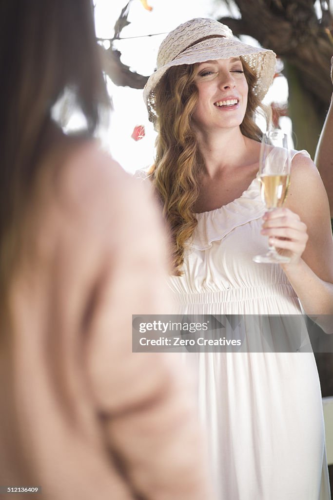 Two female friends chatting and laughing in garden wine bar