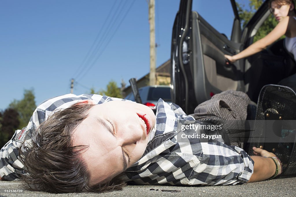 Young man hit by car lying on road