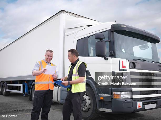 trainee truck driver receiving pass certificate from instructor - truck england stock-fotos und bilder