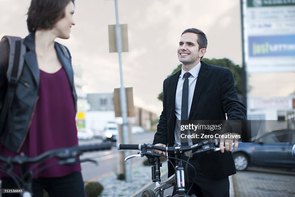 Young woman chatting to businessman whilst cycling to work