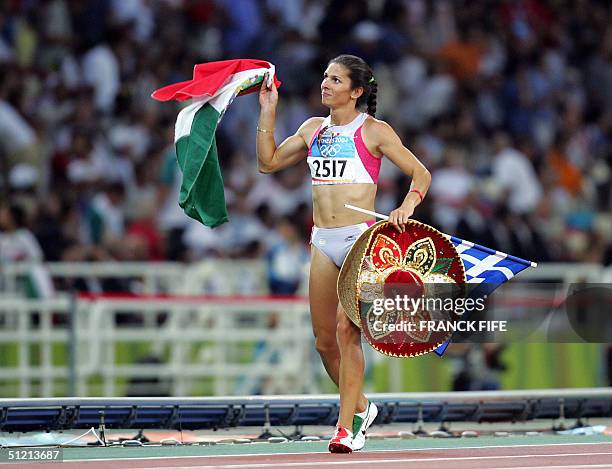 Mexico's Ana Guevara celebrates with her country's flag while running a lap of honour after she won the silver in the women's 400m final at the...