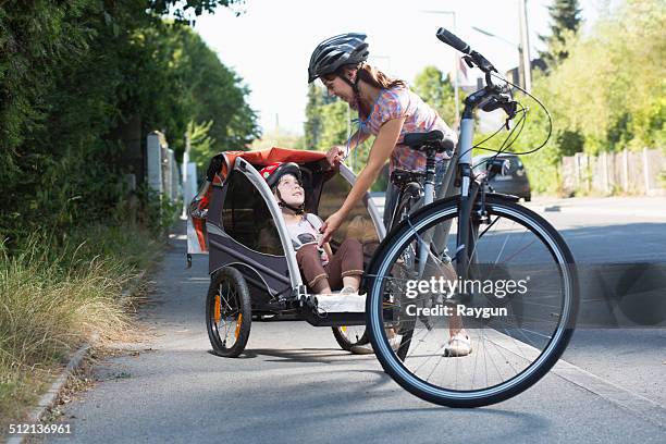 mother with daughter in bicycle trailer - cycle stock-fotos und bilder