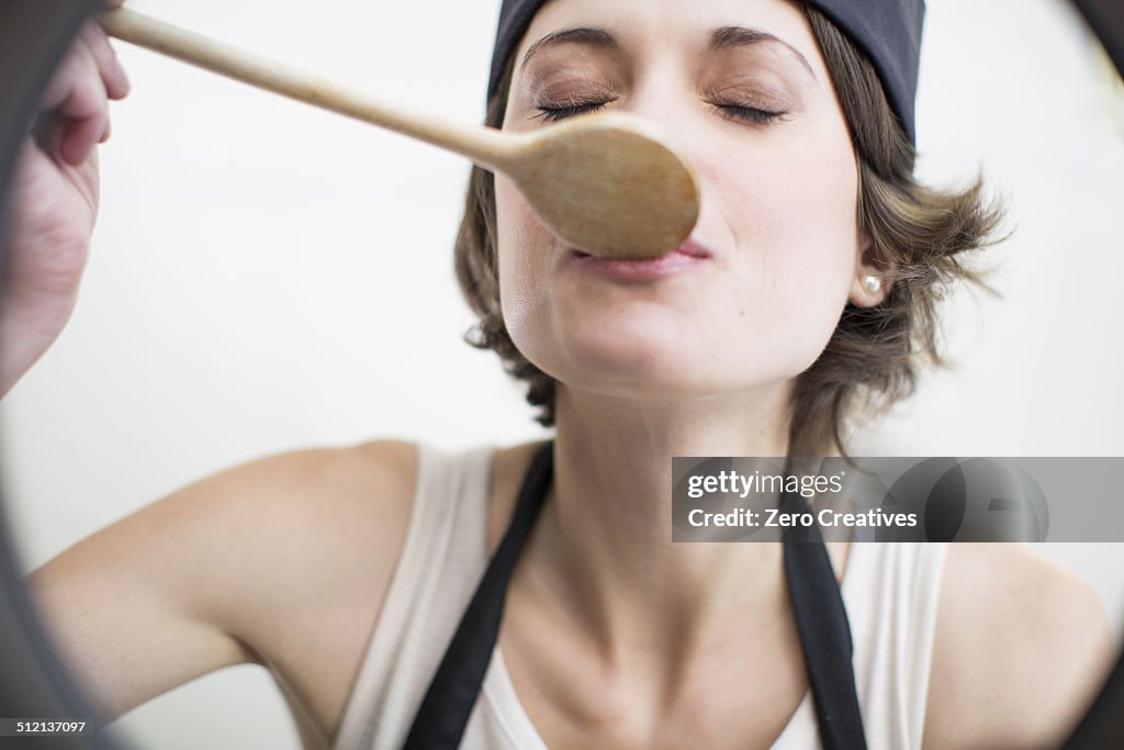 Female chef tasting food from saucepan in commercial kitchen