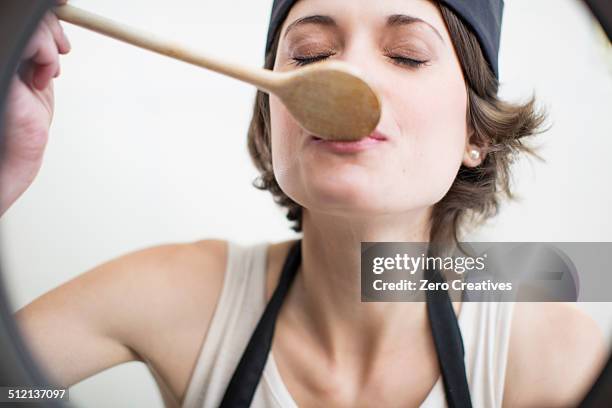 female chef tasting food from saucepan in commercial kitchen - kitchen front view stock pictures, royalty-free photos & images