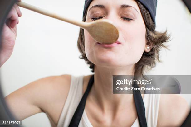 female chef tasting food from saucepan in commercial kitchen - smaka bildbanksfoton och bilder