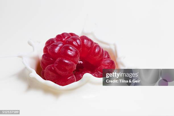 fresh raspberry splashing onto milk surface - framboos stockfoto's en -beelden