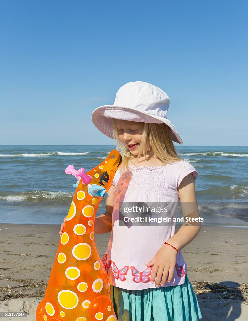 Girl holding up inflatable giraffe, Caleri Beach, Veneto, Italy