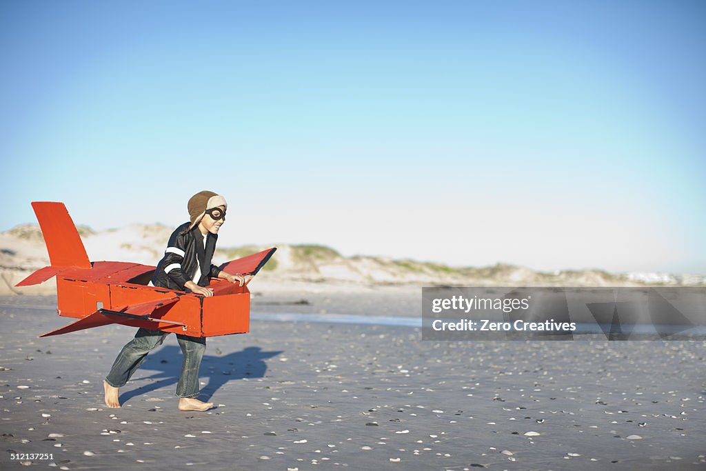 Boy running with toy airplane on beach