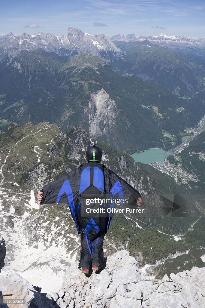 Mid adult man BASE jumping from mountain edge, Alleghe, Dolomites, Italy