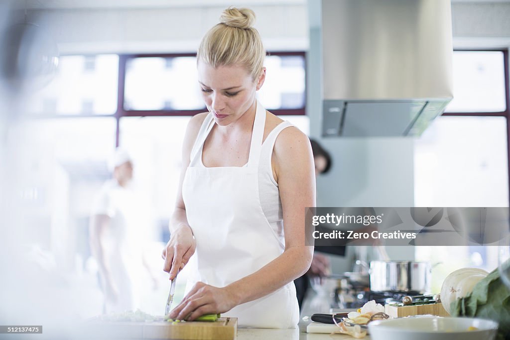 Female chef chopping vegetables in commercial kitchen