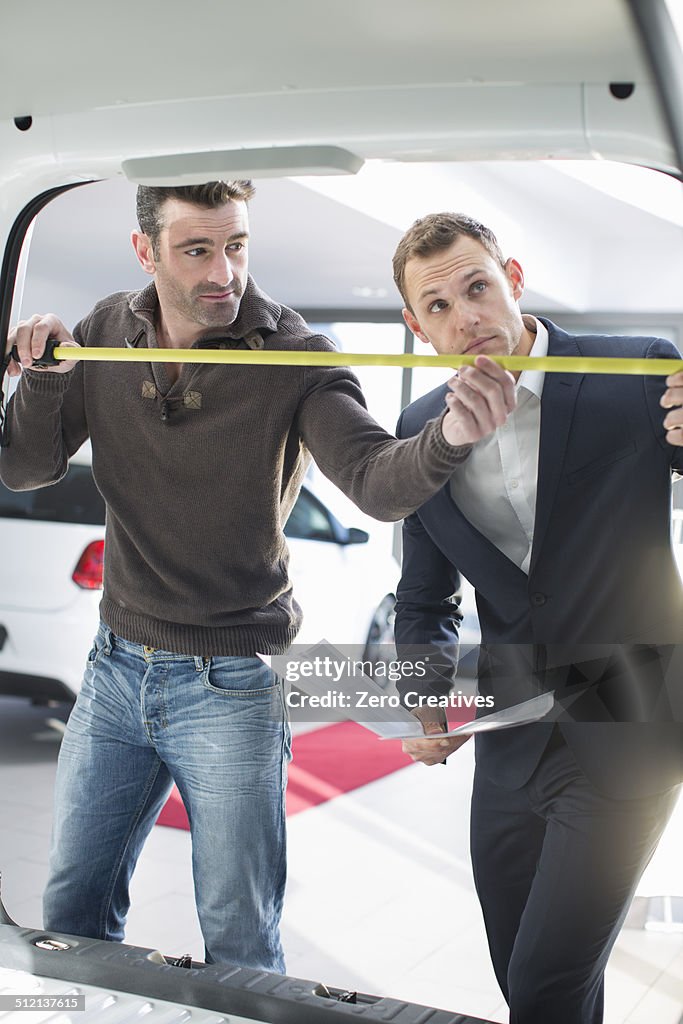 Customer and salesman measuring van interior in car dealership