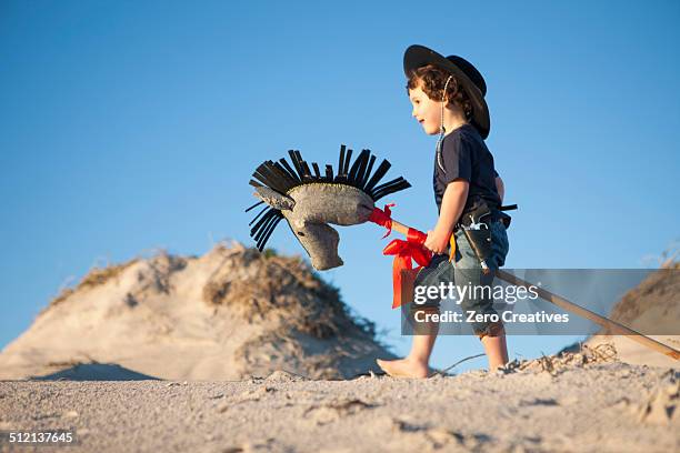 boy dressed as cowboy with hobby horse in sand dunes - hobby horse stock pictures, royalty-free photos & images