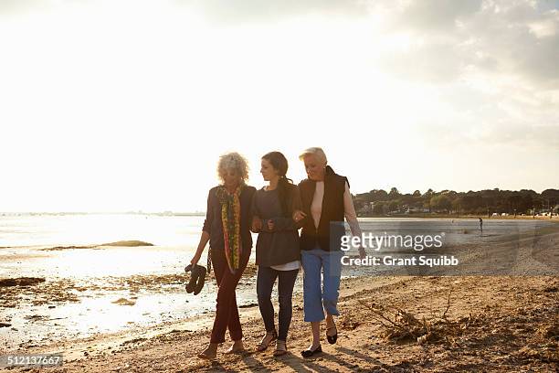 female family members walking on beach - arm in arm stock pictures, royalty-free photos & images