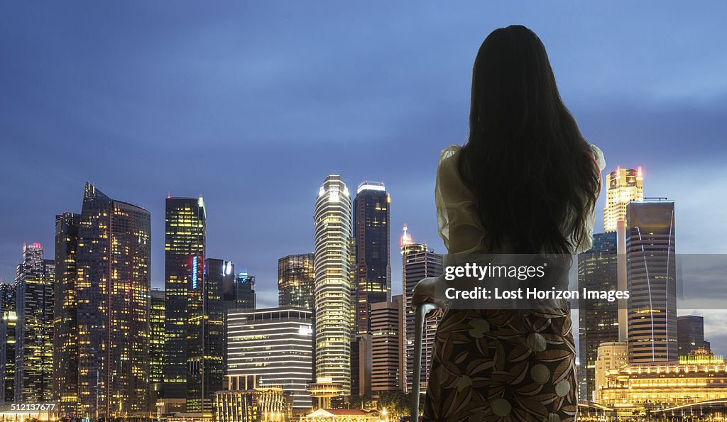 Young woman with suitcase looking at city skyline