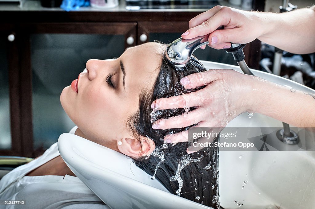 Female hairdresser rinsing young woman's hair in hair salon