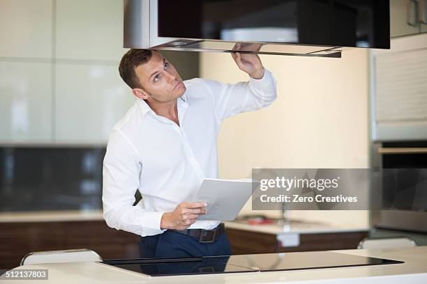 mid adult man inspecting extractor hood in kitchen showroom - checking house stock pictures, royalty-free photos & images